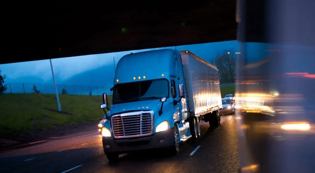 Semi-truck driving on a highway at dusk, illustrating the risks associated with semi-truck accidents.