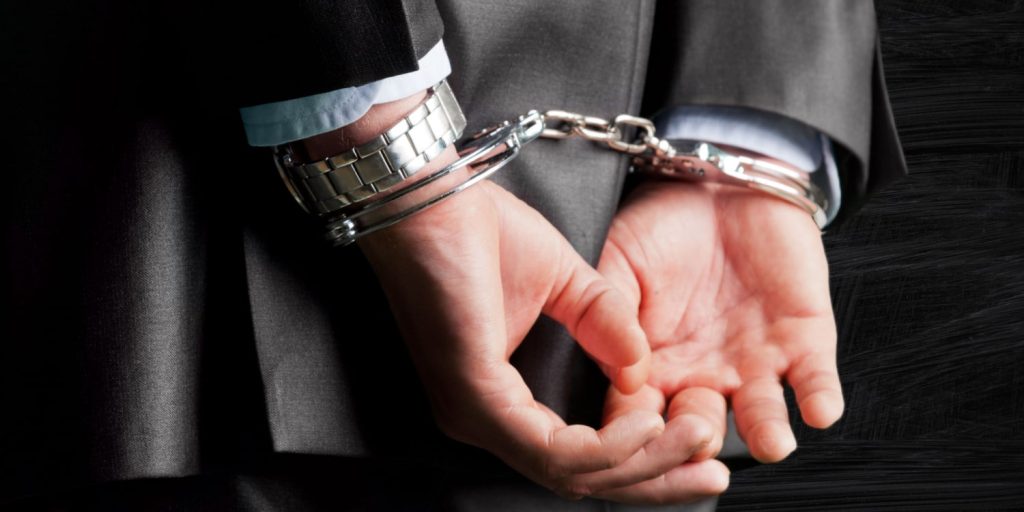 man in business suit wearing handcuffs