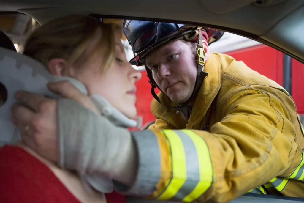 lady hurt in a car accident with a firefighter helping her