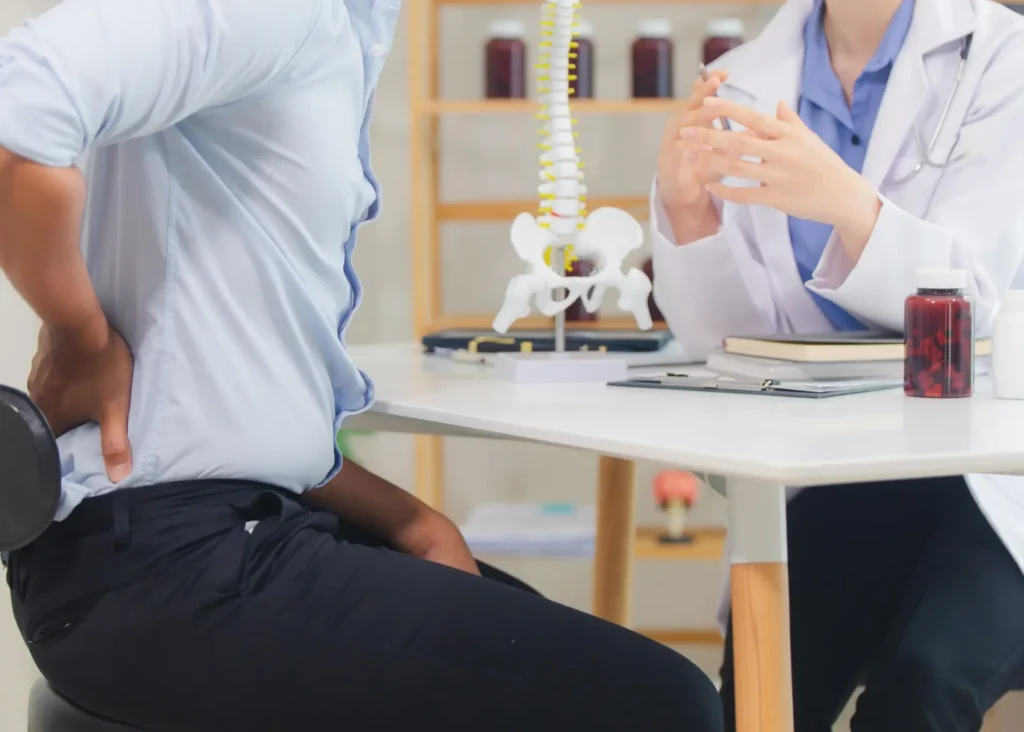 Patient discussing back pain with doctor and medical model in Tucson, Arizona.
