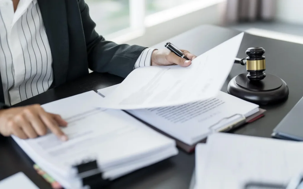 A person in a business suit reviews legal documents at a desk, with a gavel placed nearby.
