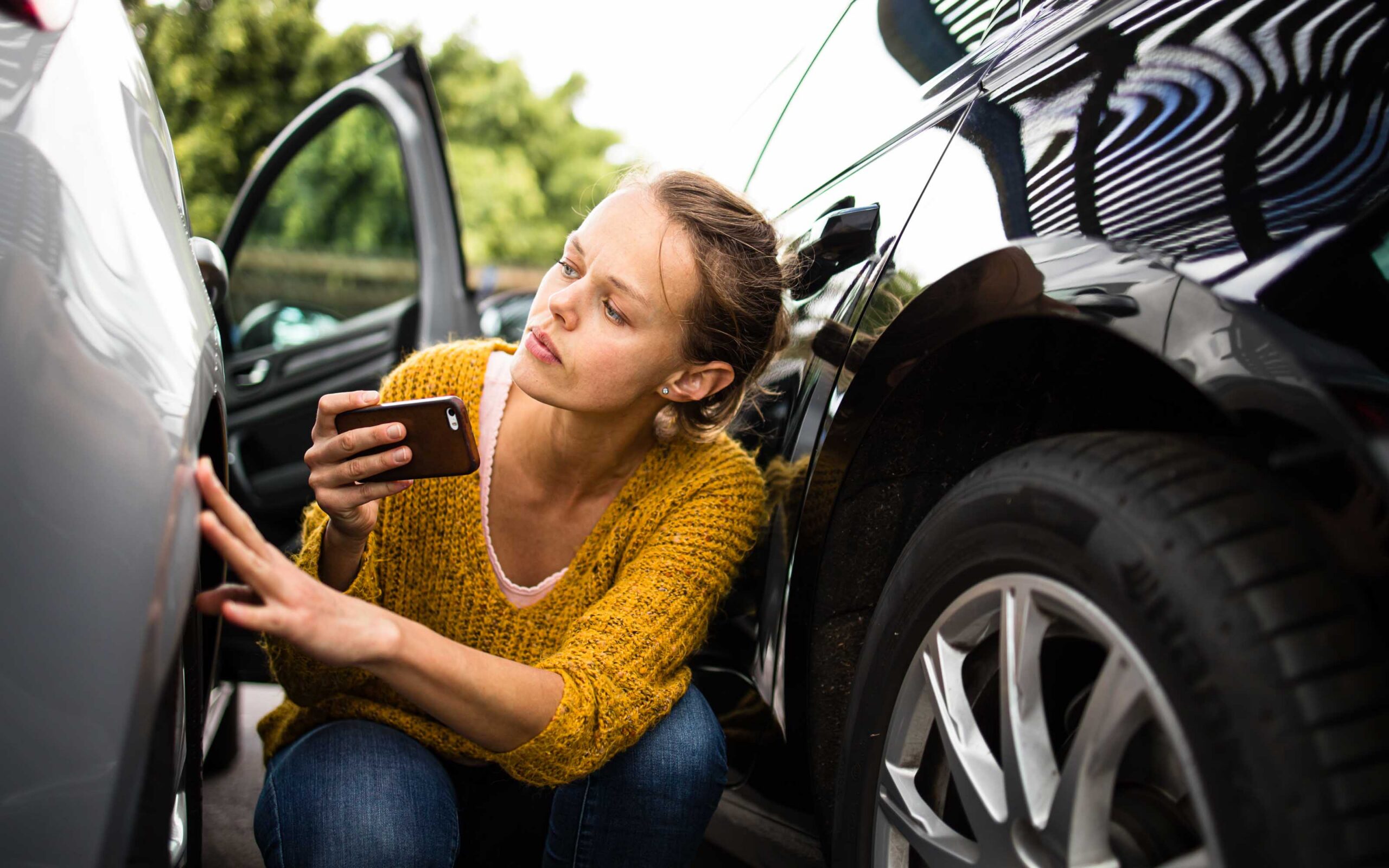 Woman inspecting vehicle damage after a car accident, illustrating Arizona car accident claim worth and personal injury compensation.