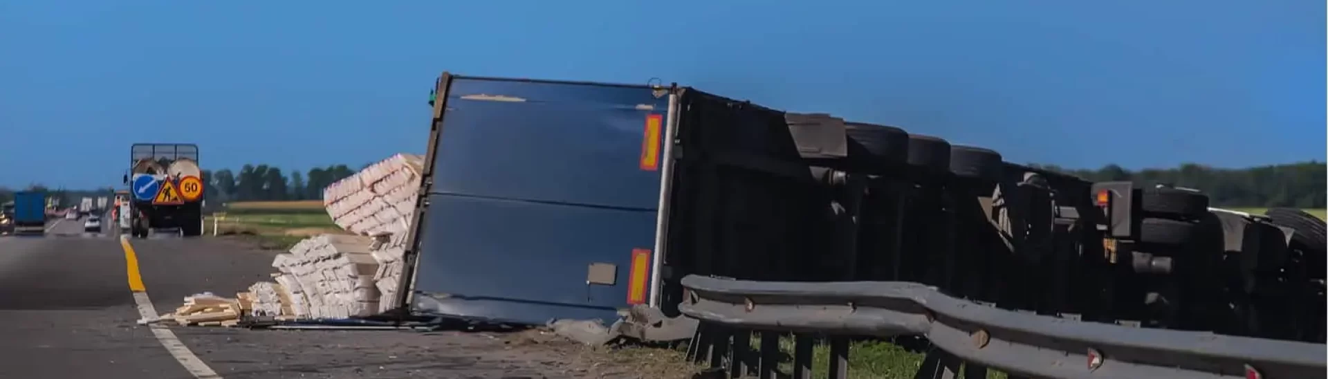 Semi-truck overturned on highway, scattered cargo, illustrating dangers of large truck accidents.